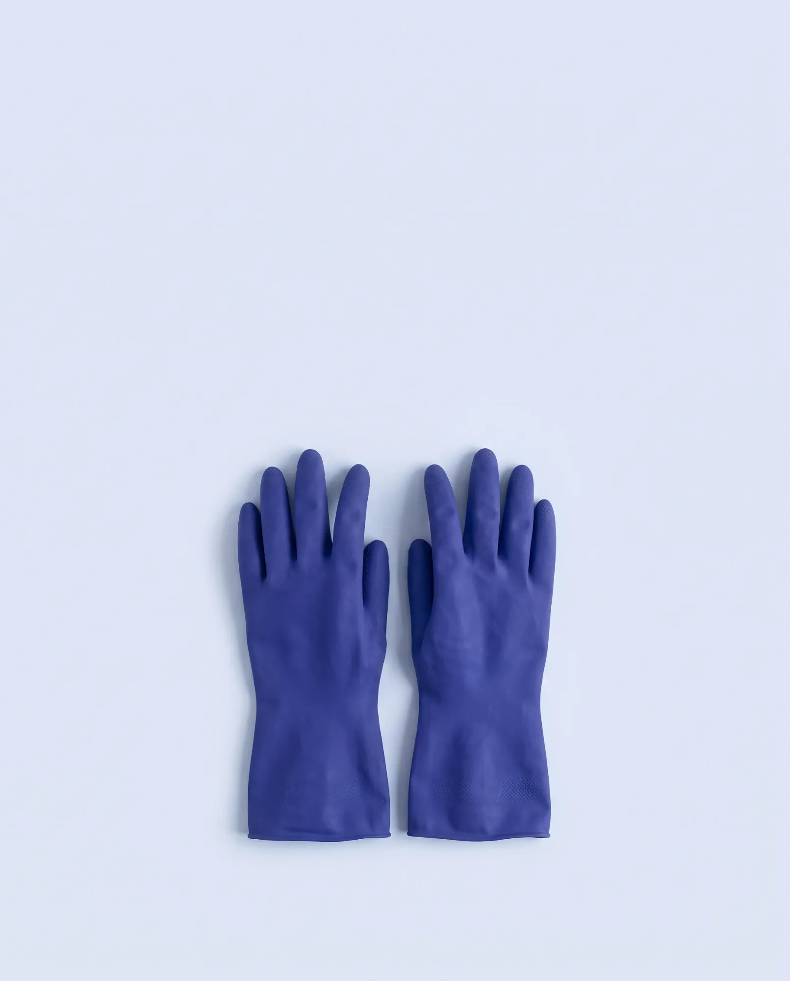 Paire de gants de ménage bleus sur fond bleu clair