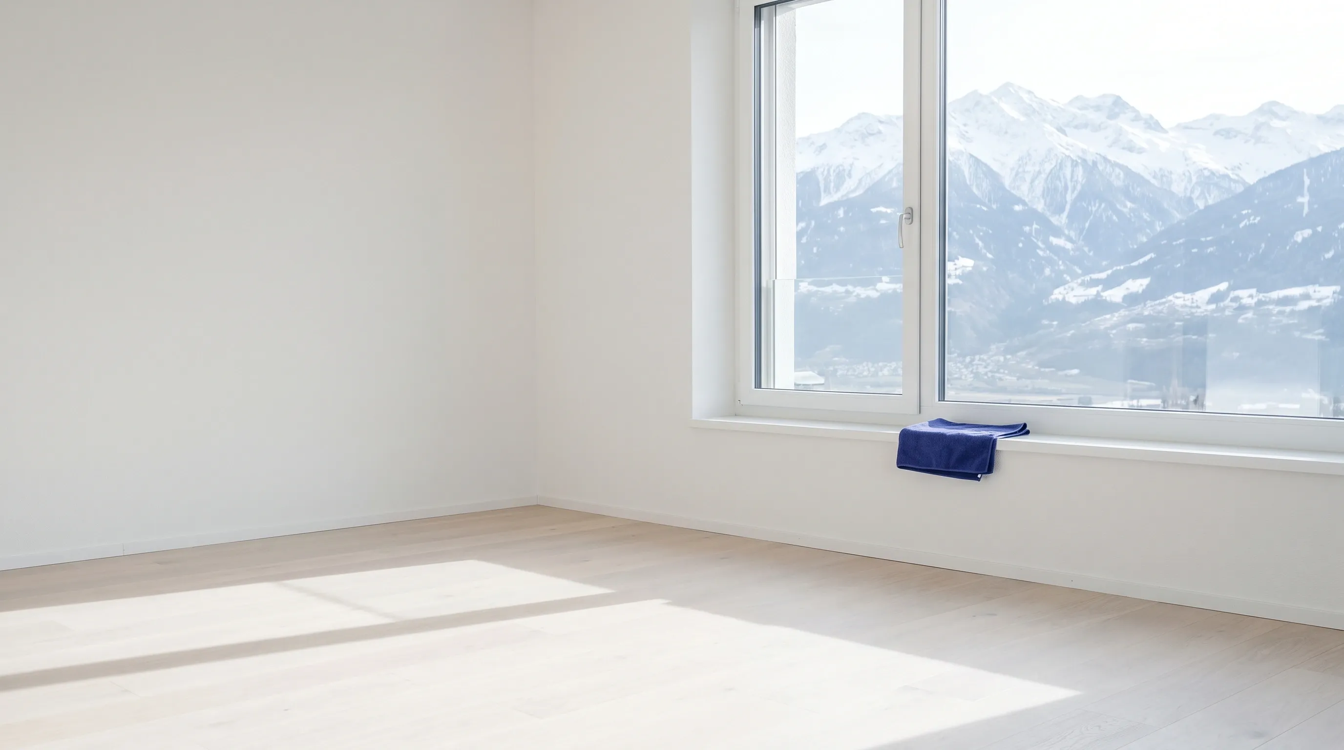 Pièce vide et lumineuse, parquet clair, fenêtre ouverte sur les montagnes enneigées